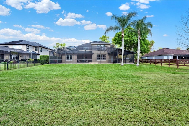 rear view of house featuring a lanai, a fenced backyard, and a lawn