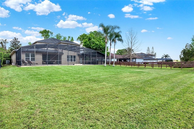 view of yard with glass enclosure and fence