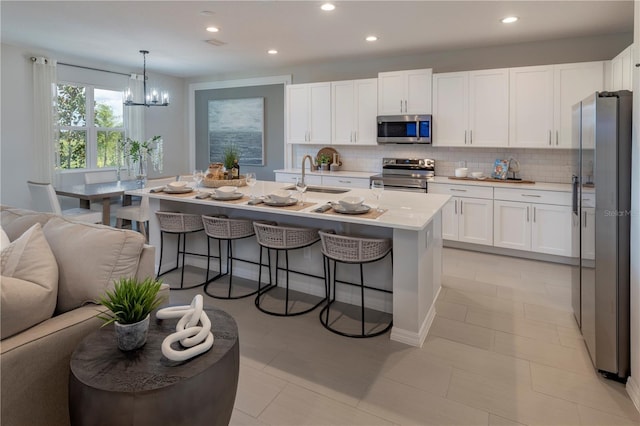 1578 Sky Lakes Dr, Saint Cloud, FL 34769 - kitchen featuring a breakfast bar, open floor plan, white cabinets, appliances with stainless steel finishes, and a sink