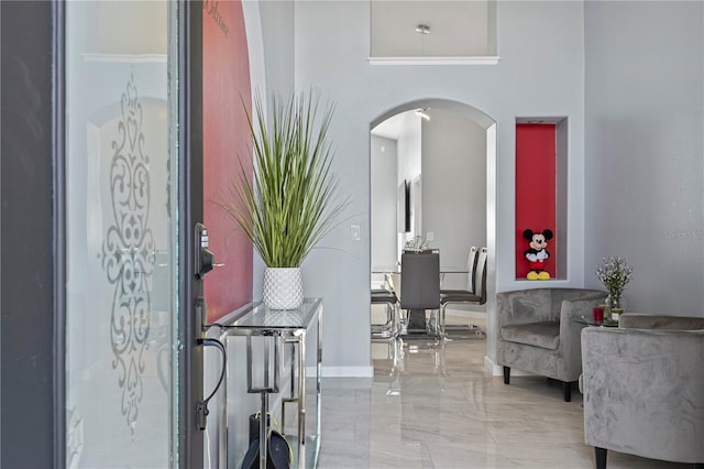 entryway featuring arched walkways and marble finish floor