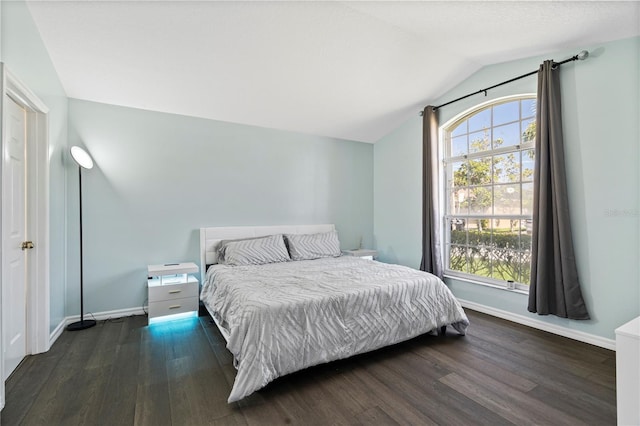 bedroom featuring vaulted ceiling, multiple windows, and wood finished floors