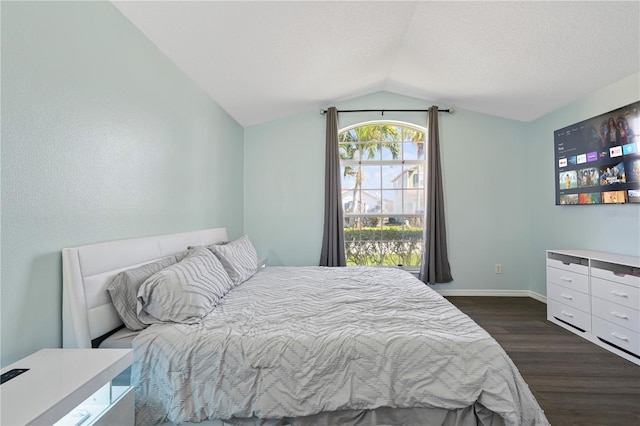 bedroom with dark wood finished floors, vaulted ceiling, baseboards, and a textured ceiling