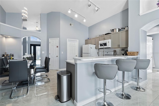 kitchen featuring white appliances, high vaulted ceiling, arched walkways, light countertops, and marble finish floor