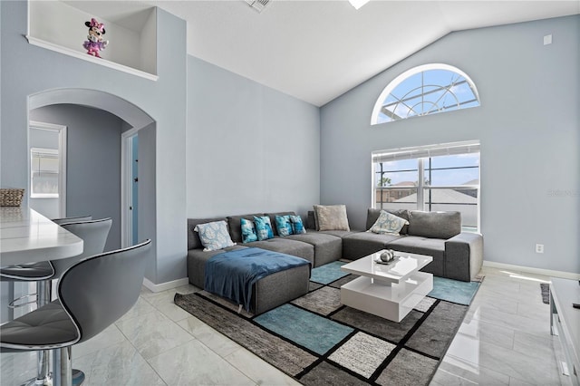 living room featuring baseboards, arched walkways, high vaulted ceiling, and marble finish floor