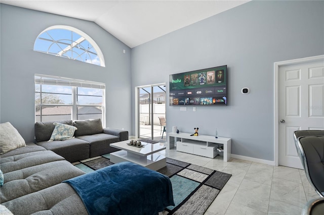 living area with plenty of natural light, high vaulted ceiling, and baseboards