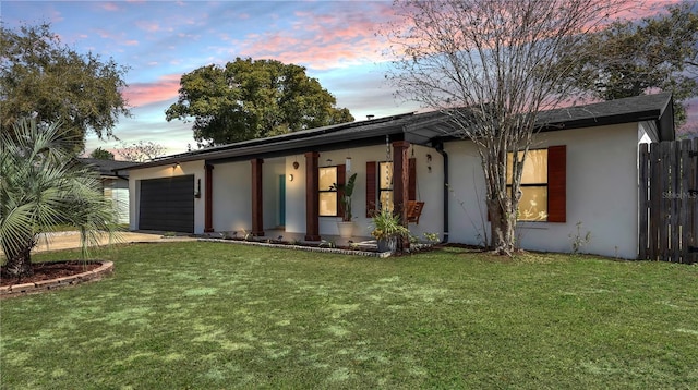 single story home with a lawn, an attached garage, fence, and stucco siding