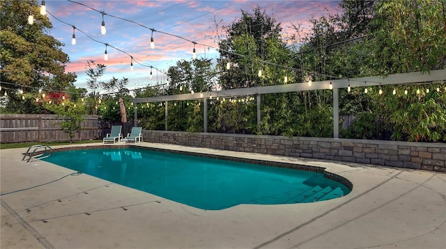 pool at dusk featuring a patio, a fenced backyard, and a fenced in pool