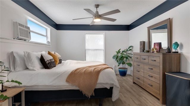 bedroom with ceiling fan, light wood-type flooring, and a wall unit AC