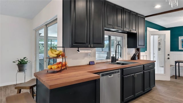 kitchen with butcher block countertops, a sink, stainless steel dishwasher, and a healthy amount of sunlight