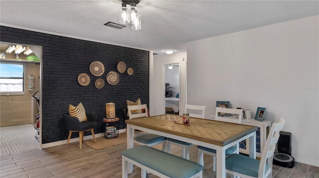 dining area with light wood-type flooring, visible vents, a textured ceiling, and baseboards