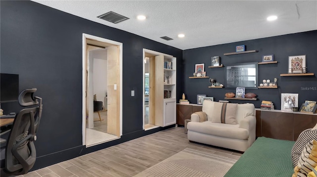 office space featuring recessed lighting, visible vents, a textured ceiling, and wood finished floors