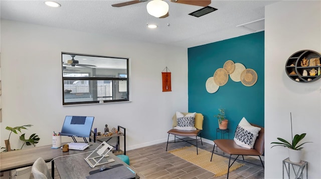 office area featuring baseboards, wood tiled floor, a ceiling fan, and a textured ceiling