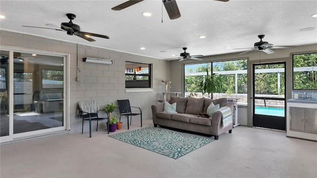 living area with concrete block wall, a textured ceiling, concrete flooring, and recessed lighting