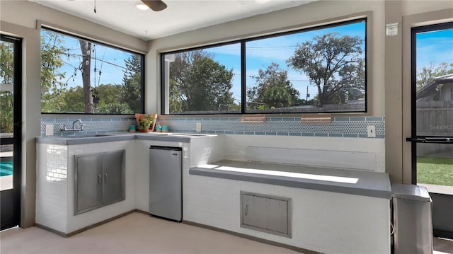 kitchen featuring tasteful backsplash, a sink, and freestanding refrigerator