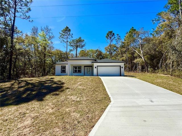 view of front facade with a garage, concrete driveway, a front yard, and stucco siding