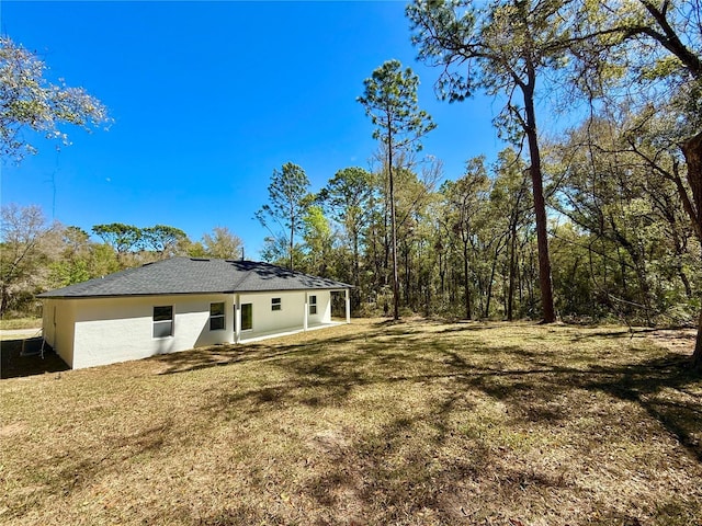 back of property featuring a yard, a patio area, and stucco siding