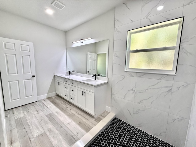 bathroom with double vanity, wood finished floors, visible vents, and a sink