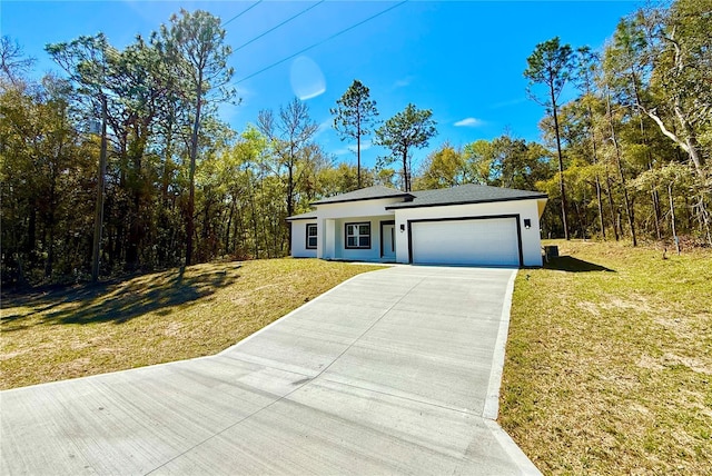 view of front of property with a garage, driveway, a front yard, and stucco siding