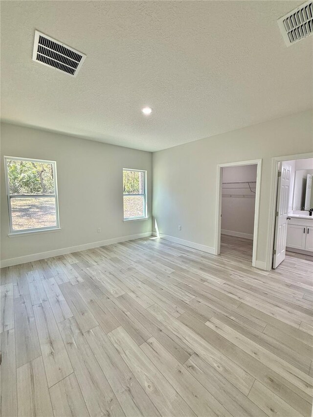 unfurnished room with visible vents, a textured ceiling, and light wood finished floors