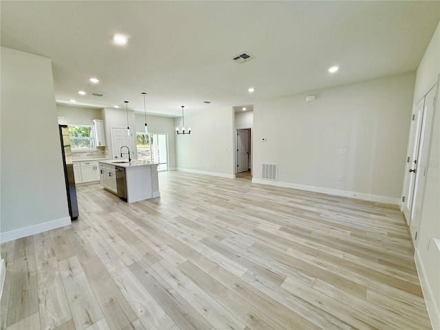 kitchen featuring visible vents, open floor plan, light countertops, stainless steel appliances, and a sink