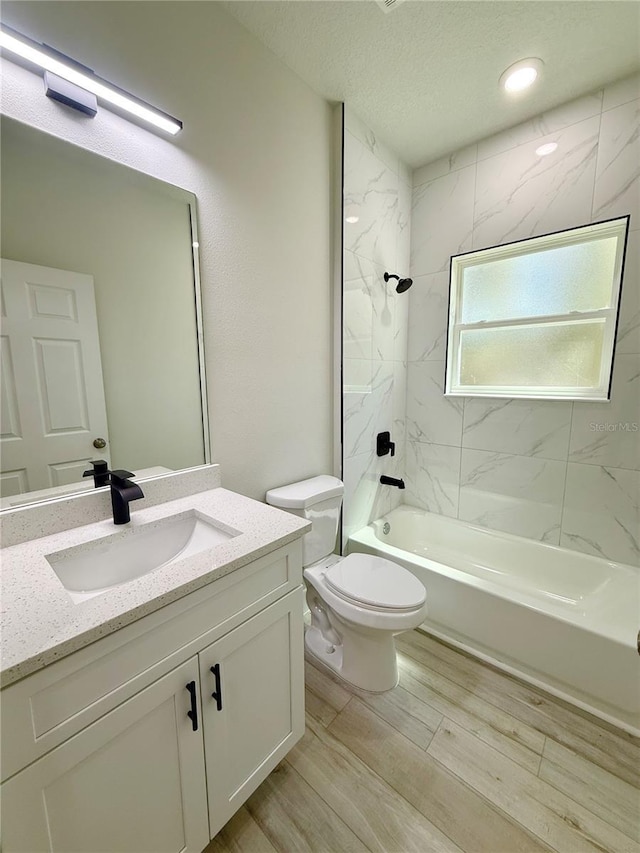 bathroom with vanity, shower / bath combination, wood finished floors, a textured ceiling, and toilet