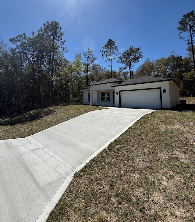 view of front of house with stucco siding, a front yard, an attached garage, and driveway