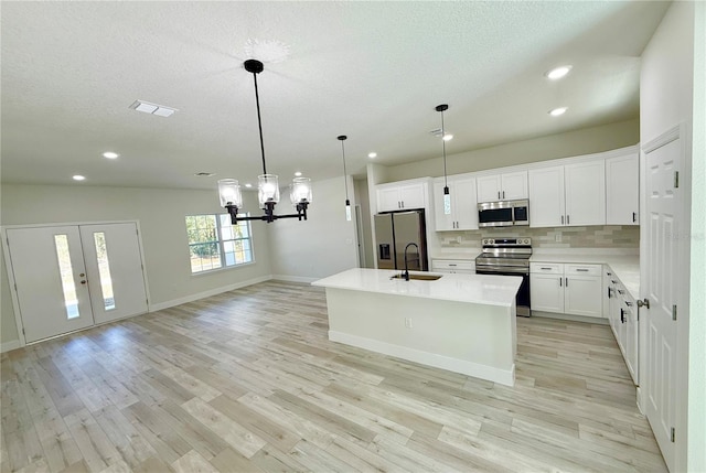 kitchen with visible vents, light wood finished floors, a sink, stainless steel appliances, and tasteful backsplash