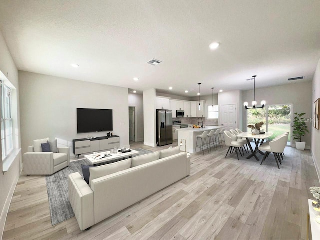 living room featuring recessed lighting, visible vents, an inviting chandelier, and light wood-style floors