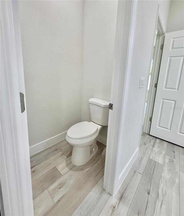 bathroom featuring toilet, baseboards, and wood finished floors