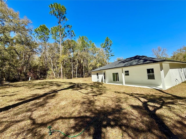 back of property with stucco siding and a lawn