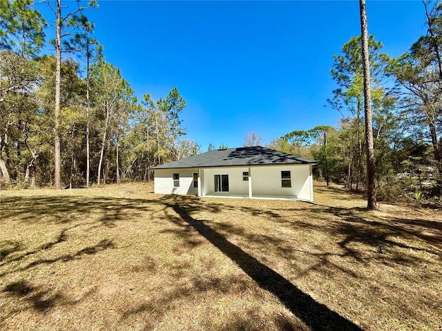 rear view of house featuring stucco siding