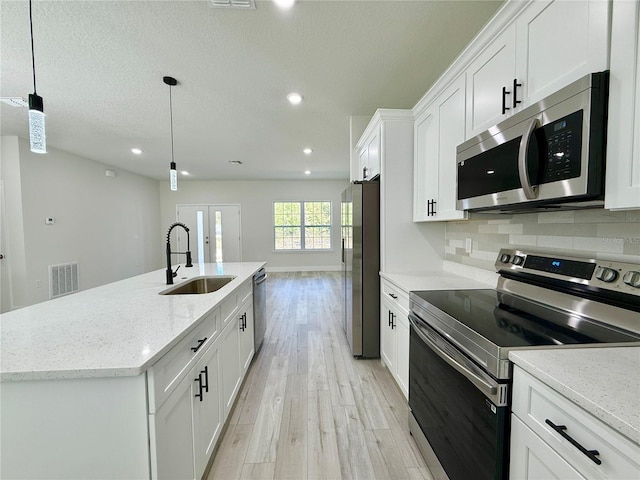 1792 W Lorraine Dr, Citrus Springs, FL 34434 - kitchen with stainless steel appliances, a sink, light wood finished floors, a center island with sink, and white cabinetry
