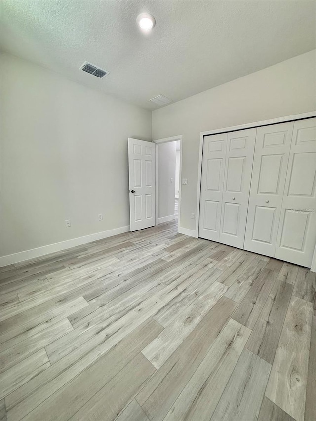 1792 W Lorraine Dr, Citrus Springs, FL 34434 - unfurnished bedroom with light wood-style flooring, a textured ceiling, baseboards, and a closet