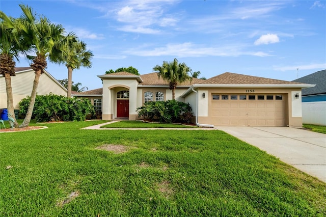 view of front of house with a front yard, driveway, an attached garage, and stucco siding