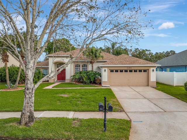 view of front of home featuring an attached garage, fence, concrete driveway, stucco siding, and a front lawn