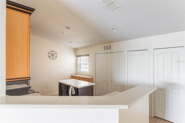 kitchen with light tile patterned floors, light countertops, visible vents, and a center island