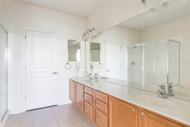 bathroom with a stall shower, double vanity, a sink, and tile patterned floors