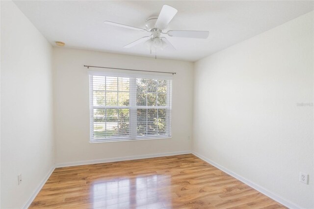 spare room with light wood finished floors, a ceiling fan, and baseboards