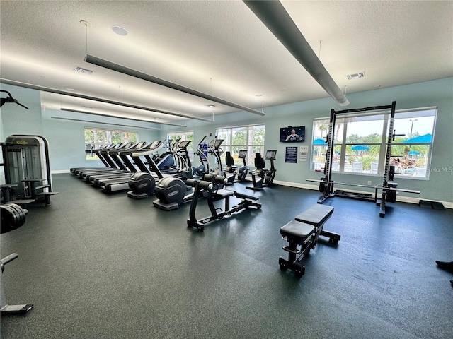 workout area with a textured ceiling, visible vents, and baseboards