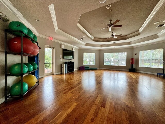 unfurnished living room with crown molding, a raised ceiling, visible vents, a textured ceiling, and wood finished floors