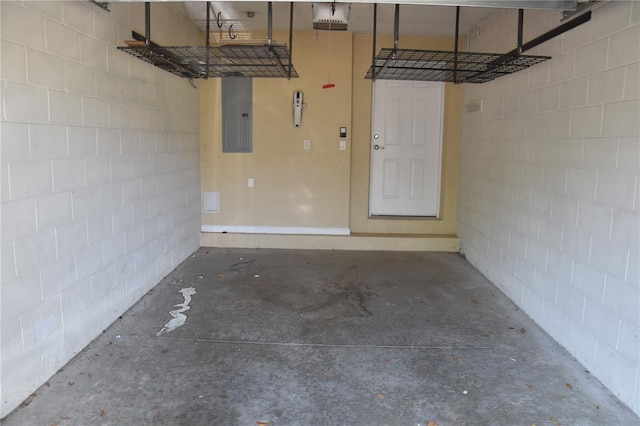 garage featuring concrete block wall, electric panel, and a garage door opener