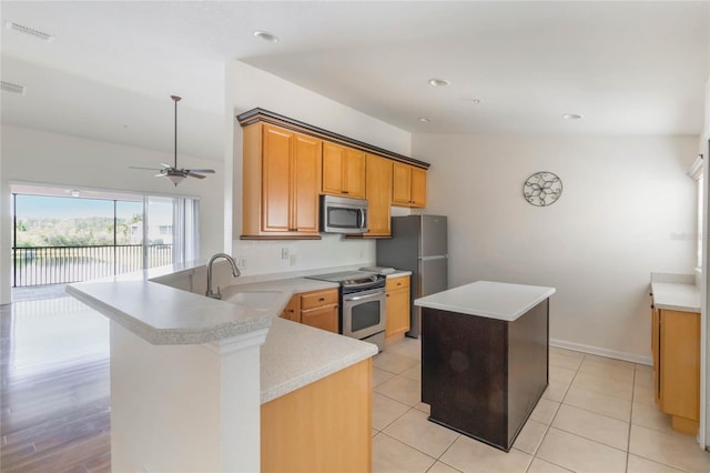 kitchen with visible vents, a center island, a peninsula, stainless steel appliances, and a sink