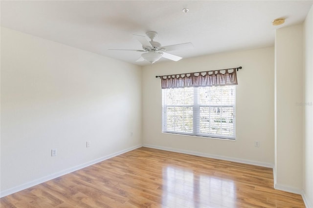 spare room featuring ceiling fan, light wood finished floors, and baseboards