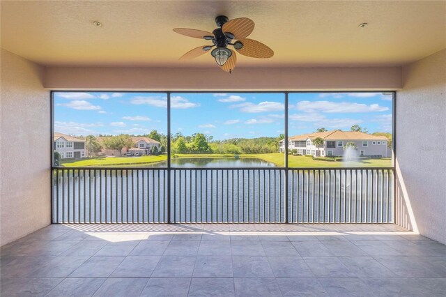 unfurnished sunroom featuring ceiling fan and a water view