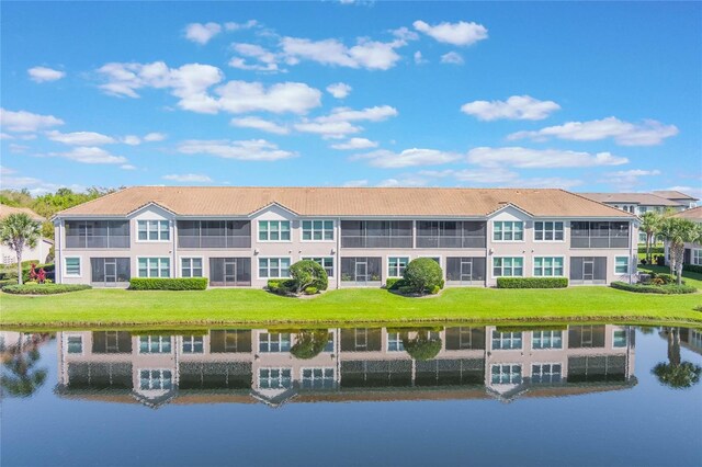 rear view of house with a lawn, a water view, and a sunroom