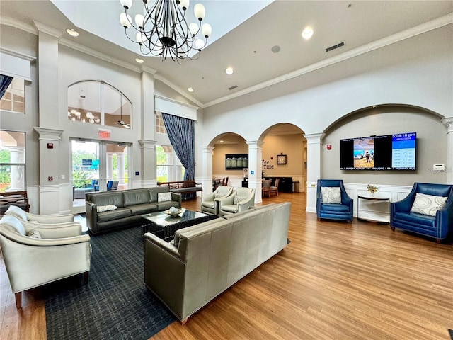 living area with decorative columns, visible vents, a wainscoted wall, wood finished floors, and high vaulted ceiling