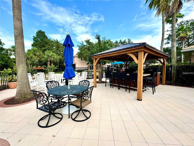 view of patio featuring a gazebo, fence, outdoor dry bar, and outdoor dining space