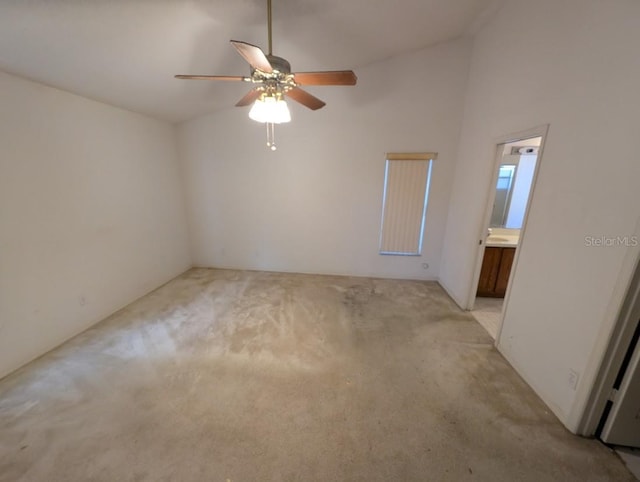 spare room featuring vaulted ceiling, ceiling fan, and light colored carpet