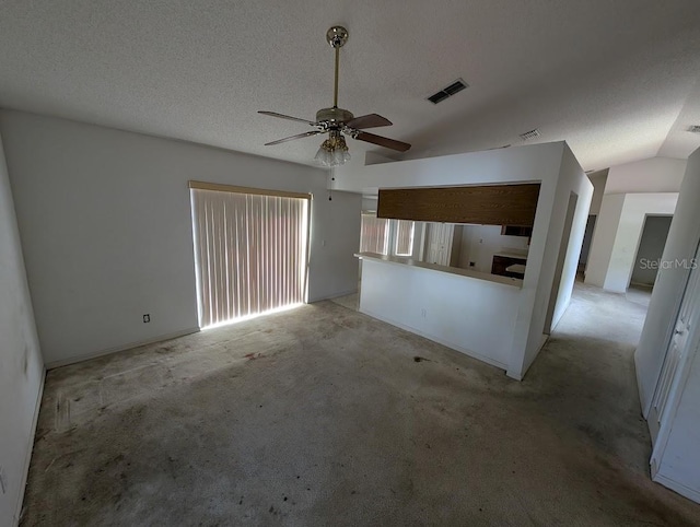 unfurnished living room with light carpet, visible vents, ceiling fan, vaulted ceiling, and a textured ceiling