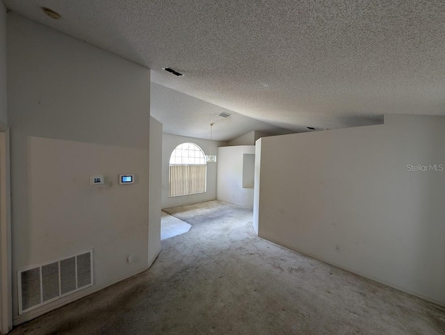 empty room with lofted ceiling, carpet floors, a textured ceiling, and visible vents